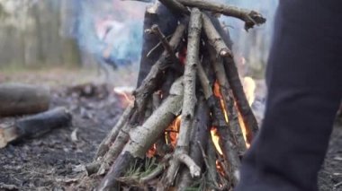 Yürüyüş sırasında ormanda bir yangın, spor ayakkabıları içinde ayaklar ateşin yanında yürür