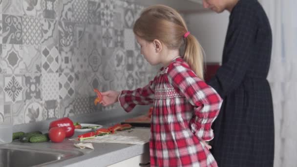 Маленькая девочка помогает маме готовить закуски.. — стоковое видео