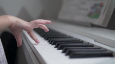 Yakın plan, küçük çocukların elleri elektronik piyanonun tuşlarına basıyor.