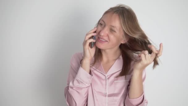 Une femme brune heureuse dans une chemise rose parle au téléphone — Video