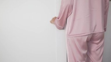 Pembe takım elbiseli bir kadın kapıyı açar ve odadan çıkar.