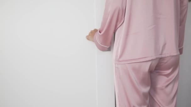 絹のピンクの家のスーツを着た女性がドアを開けて部屋を出る — ストック動画