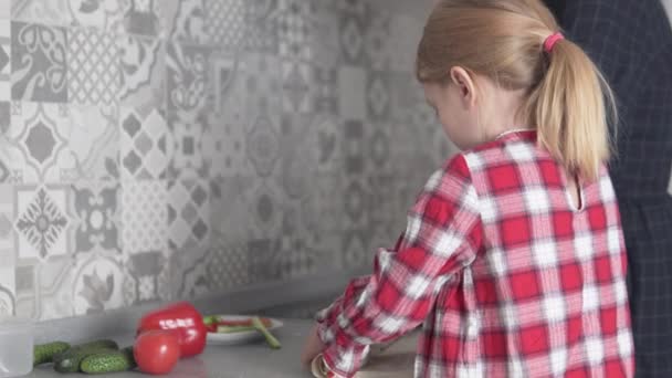 Een klein meisje en haar moeder koken pitabrood met vis en groenten thuis in de keuken — Stockvideo