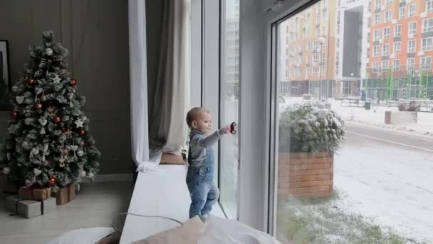 Ein kleiner Junge blickt an einem Weihnachtsmorgen in Russland aus dem Fenster — Stockvideo