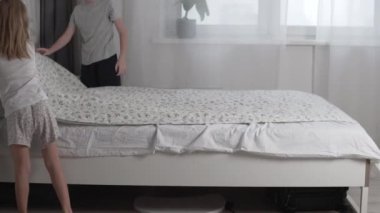 Çocuklar, bir oğlan ve bir kız, sabahları anne babalarının yatağını temizlerler.