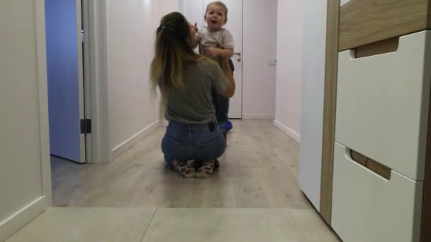 A young mother kisses her young son and holds her at home — Stock Video