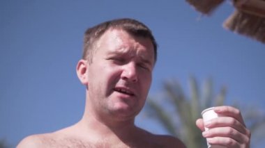 Yakın plan, Mısır 'da plastik bardaktan bira içen kıllı bir adam.