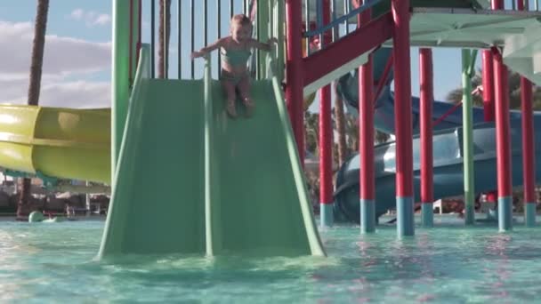 Tiroteio em câmera lenta, uma menina desce um slide em um parque aquático em um hotel no Egito — Vídeo de Stock