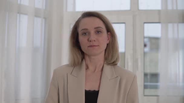Um close-up, uma mulher de negócios em um casaco fala sobre seus sucessos na câmera — Vídeo de Stock