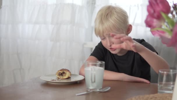 Een blonde jongen zet een kunstgebit in een glas schoonmaakdoek voor het eten thuis — Stockvideo