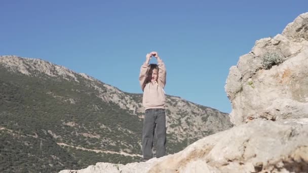 Το κοριτσάκι σκαρφάλωσε στο βουνό και σήκωσε τα χέρια ψηλά. — Αρχείο Βίντεο