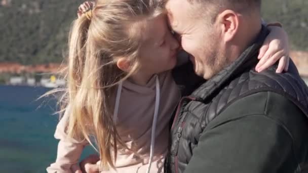 Una bambina abbraccia e bacia suo padre durante una passeggiata sulla spiaggia — Video Stock