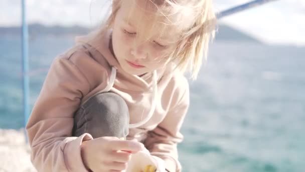 Een meisje eet snel eten aan zee — Stockvideo