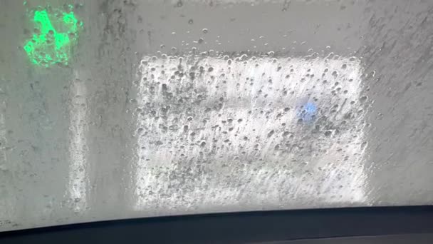 Αφροί αφρού από το παρμπρίζ του αυτοκινήτου στο αυτόματο πλυντήριο αυτοκινήτων — Αρχείο Βίντεο