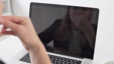 Bir iş kadını, ofiste sakız çiğneyen bir bilgisayarla kameraya dokunuyor.