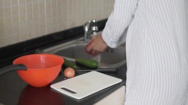Kadın bir ev hanımı sebze salatası için domates kesiyor..