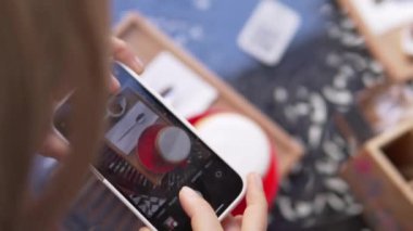 Yakın planda, bir kız kafede telefonuyla bir fincan kapuçino içerken fotoğrafını çekiyor. Kadın bir blogcu Edv 'inin fotoğrafını çekiyor..