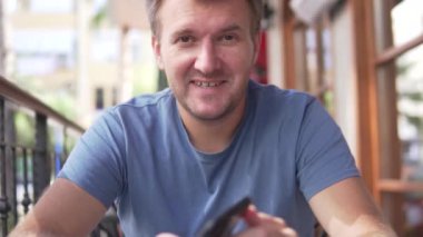 Telefonlu bir adam sabah kahvaltını bir kafede bekliyor..