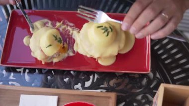 Sabah bir restoranda nefis yumurta ve ekmek kahvaltısı bir adam tabağın bir parçasını kesiyor.