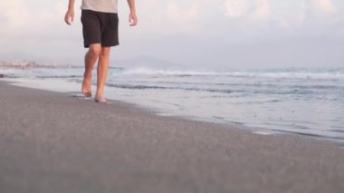 Genç bir çocuk deniz kenarında kumlu bir sahil boyunca yürüyor, ayaklarına yakın, Türkiye, Alanya, Eylül.