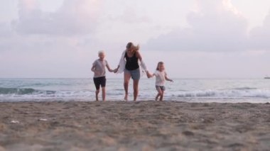 Çocuklu mutlu bir kadın kumsalda ağır çekimde koşar. Türkiye, Alanya