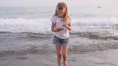 Güzel küçük bir kız yazın deniz kenarında sahilde yürür. Türkiye, Alanya