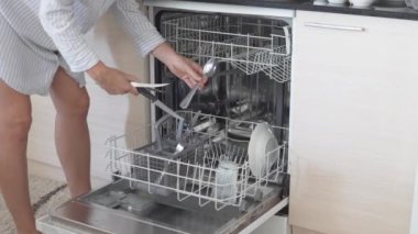 Bir kadın sabahları bulaşık makinesini evde dolduruyor..