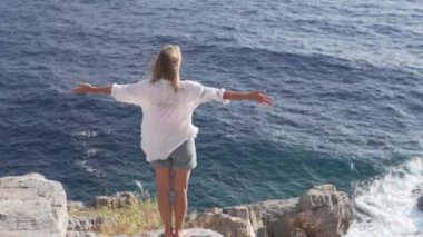 Arkadan bak. Bir kadın kollarını Akdeniz 'in arka planına doğru açıyor. Mutlu turist.