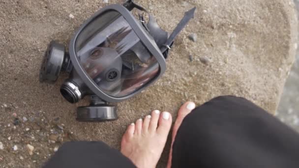 海に面した女性の足の裏に石の上にガスマスクがかかっている — ストック動画