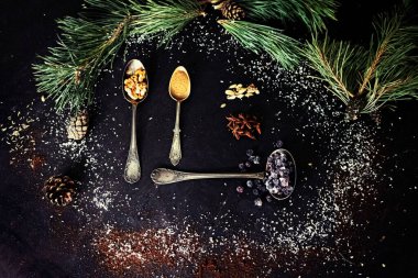 christmas background with fir branches, pine cones, cinnamon and anise stars on black wooden table. top view