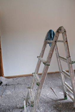 Merdiven, silindir ve boya silindiri. Boya almaya hazır boş bir odada boya kovaları. Duvarları boyamak, yeniden yapılandırma işleri.