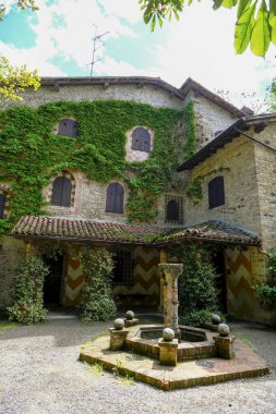 Sarmaşık yapraklı Grazzano-Visconti kale duvarları, ortaçağ çeşmesi. Ortaçağ mimarisi, bina. İtalya, Emilia-Romagna