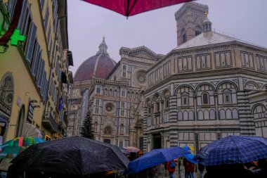 Floransa, İtalya: Santa Maria del Fiore Kubbesi dramatik gökyüzünde, binalarda, yağmurlu bir günde şemsiyeli insanların arasında.