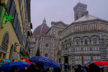 December 2021 Florence, Italy: Dome of Santa Maria del Fiore,   Battistero di San Giovanni, Piazza San Giovanni close-up across dramatic sky, umbrellas