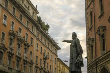 Ugo Bassi heykeli Ugo Bassi caddesinde turuncu binaların karşısında ve gökyüzü Bolonya, İtalya