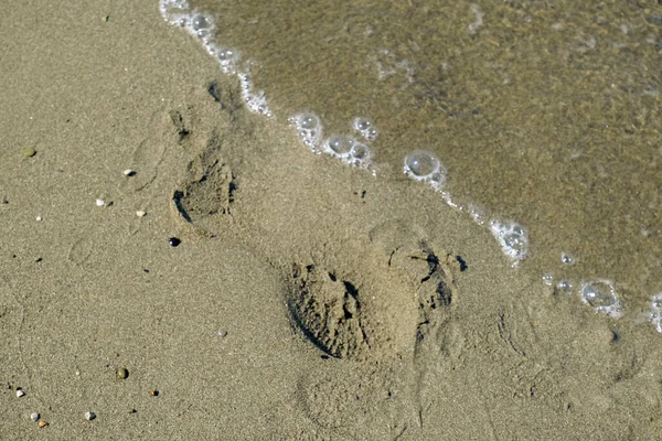 波と砂のビーチのクローズアップ 地平線の間の足跡 海辺の背景 コピースペース 夏の背景 — ストック写真