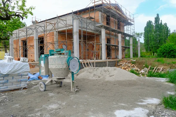 Yakın plan çekimde beton karıştırıcı. Aletleri ve binaları olan bir inşaat alanı. İnşaattaki ev, yakın plan. İnşaat alanı.