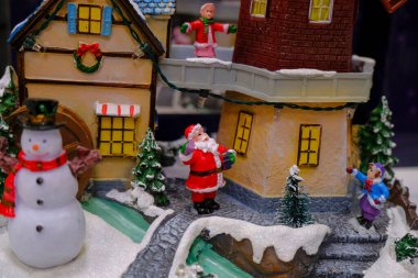 santa claus in the snow across cute colorful houses and snow man. Christmas scene. Christma decoration. Postcard