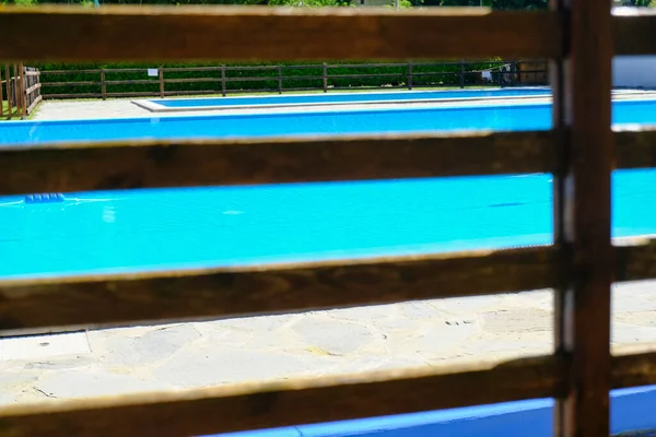 木製の柵の向こうの晴れた日にプールの水を泳ぐ 水面だ ホテルのリゾート 夏のアクティビティ — ストック写真