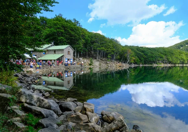 Santo Gölü, Lago Santo dağların ve ormanların ötesinde. Göl kenarında turistlerle dolu bir barınak. Ulusal Park Appennino Tosco-Emiliano. Lagdei, Emilia-Romagna
