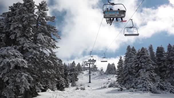 Solig dag i den snötäckta berg och skidliften flyttas upp med skidåkare. — Stockvideo