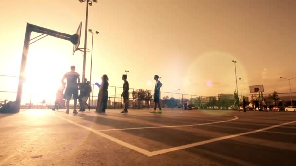 Jogando basquete, no pôr do sol, por trás do fio de purê — Vídeo de Stock