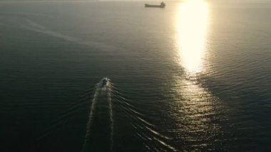 Balıkçı teknesi havası. Bu video günbatımında kargo gemisine giden bir balıkçı teknesini gösteriyor..