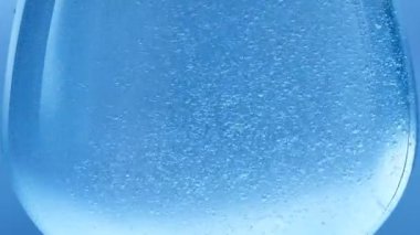 Kabarcık Arkaplanı. Mavi arkaplanda geniş bir bardakta yükselen köpüklerin yakın görüntüsü.