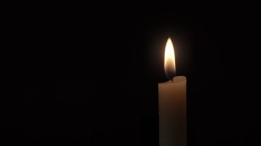 Mum. Siyah arka planda yanan tek bir mum alevinin yakın plan görüntüsü.