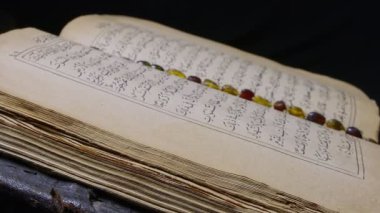 Qouran Kitap ve tespih duası. 4K Kararı 38402160 Qouran kitabı ve koyu arkaplanda dönen tespih..