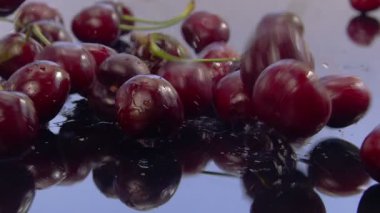 Taze kirazlar su dolu bir ayna yüzeyine düşer. Yüksek kalite 4k görüntü