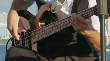 Bass Player 'ın Elleri Kapalı, Bass Gitar' la Rock Müzik Çalıyor. Açık hava düğün partisinin olduğu yerde, Güzel deniz manzaralı bir yerde..