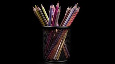 Metal bir kutuda renkli kalemler. Metal kalem kılıfındaki renkli kalemler izole edilmiş, siyah arka planda dönüyorlar..
