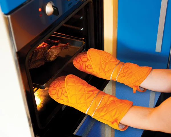 Woman in kitchen gloves  near oven